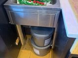 a trash can in the corner of a kitchen with a sink