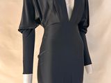 La robe est noire, avec un décolleté en V et des manches longues.