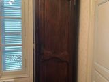 une chaise dans un coin de la pièce, à côté d'une grande armoire en bois