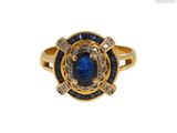 gros plan d'une bague en or avec une pierre bleue et des diamants