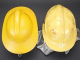 two yellow hard hats sitting next to each other on a black surface