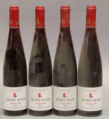 quatre bouteilles de vin sont alignées sur une surface blanche