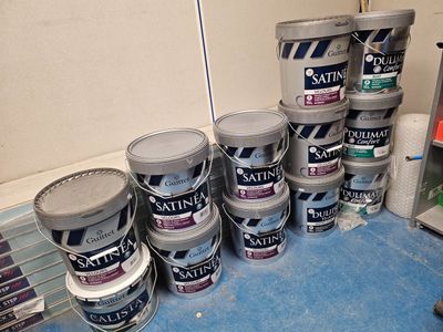 de nombreux pots de peinture posés par terre à côté d'un réfrigérateur