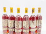 six bouteilles de vin alignées sur une surface blanche
