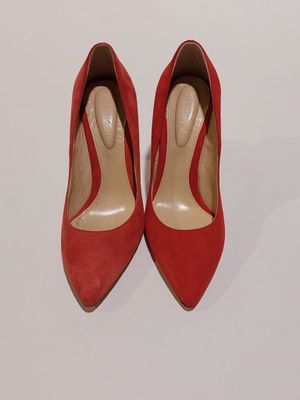 des chaussures à talons hauts rouges posées sur une surface blanche, avec un fond blanc