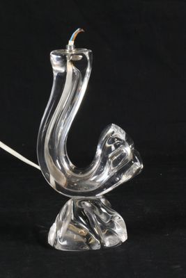 une lampe en verre transparent dont le pied a la forme d'un oiseau, sur fond noir