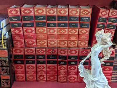 a figurine of a woman standing in front of a stack of books