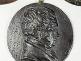 three bronze medallions of a man and a woman on a white surface