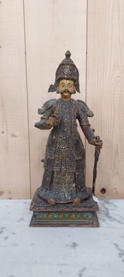 une statue représentant une femme tenant une canne, posée sur une table