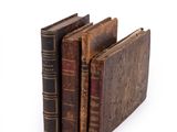 several old books are stacked on top of each other on a white surface