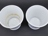 two white cups with brown spots on them on a black surface