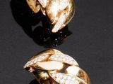 une paire de boucles d'oreilles en or et diamants posées sur un fond noir
