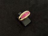 gold ring with pink stones on a black surface