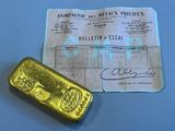 gold bar next to a receipt on a blue surface