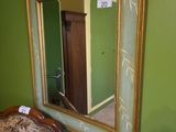 un miroir accroché au mur à côté d'une chaise dans une pièce