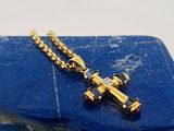une croix en or posée sur une pierre bleue, accompagnée d'une chaîne