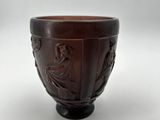 a brown bowl with carvings on it on a white surface