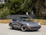 a grey porsche parked in a driveway with trees in the background
