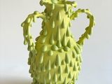 un vase jaune posé sur une surface blanche