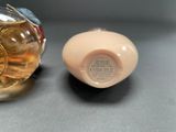 a small bottle of perfume next to a smaller bottle of perfume
