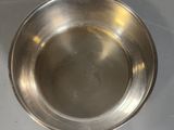 a silver bowl on a stand on a white surface