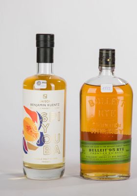 Deux bouteilles d'alcool sont posées l'une à côté de l'autre sur une surface blanche.