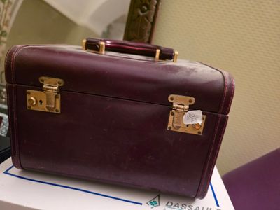 une valise violette posée sur une boîte blanche