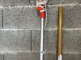 a shovel and a stick on the ground next to a brick wall