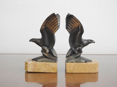 paire de serre-livres en bronze représentant des aigles, posés sur un socle en marbre, sur une table