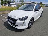 La voiture blanche est garée sur le parking, près de la pelouse.