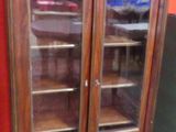 un grand meuble en bois avec des portes en verre dans une pièce