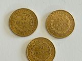 three gold coins sitting on top of a white surface
