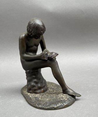 statue en bronze représentant un garçon assis sur un rocher en train de lire un livre