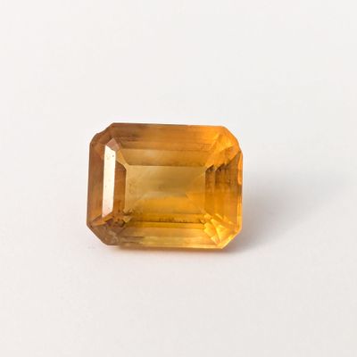 gros plan d'une pierre de saphir jaune sur une surface blanche