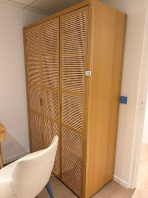 une chaise blanche placée devant une armoire en bois
