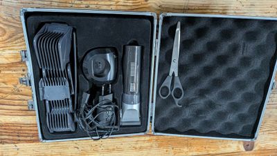 une trousse métallique contenant des ciseaux, des peignes et un sèche-cheveux
