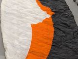 a large orange and white kite on the ground