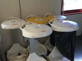 many toilets and trash cans in a room