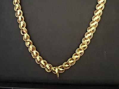 un gros plan d'un collier à chaîne dorée posé sur une surface noire