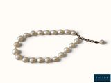 a close up of a bracelet with pearls on a white background