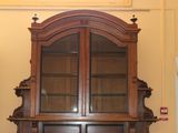 a wooden cabinet with a glass door in the corner of the room