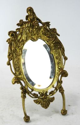 un miroir doré orné d'un oiseau, posé sur un socle