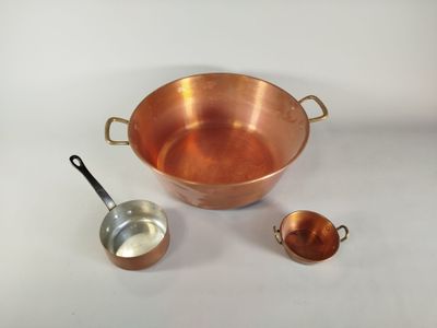 une casserole en cuivre avec une louche et une cuillère doseuse