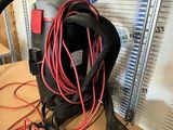 a black bag with a red cord and a pair of pliers next to it