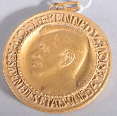 médaille d'or représentant le profil d'un homme sur fond blanc