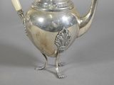 a silver tea pot with a handle on a table