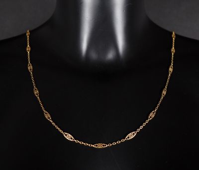 un collier à chaîne en or au motif raffiné, posé sur un mannequin