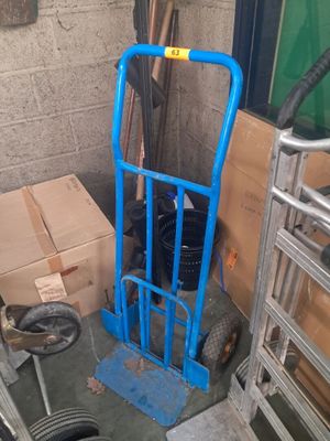 un diable bleu posé à côté d'une pile de cartons