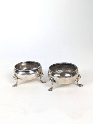 deux plats en métal argenté munis d'anses, posés sur des socles, disposés sur un fond blanc