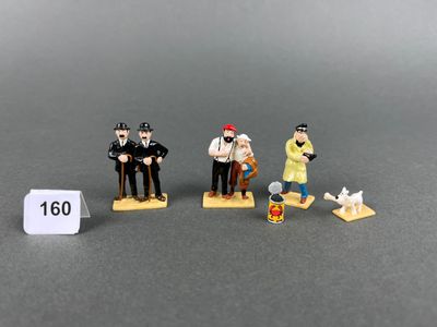 three figurines of a man and a woman sitting on a bench
